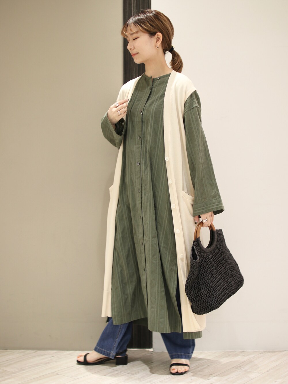 グリーン系のワンピース、ホワイト系のニット/セーター、ブラック系のトートバッグを着用したレディースの春コーディネートの2枚目の写真