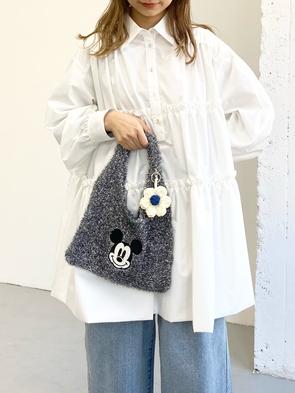 ホワイト系のワンピース、ブルー系のデニムパンツ、ブラック系のトートバッグを着用したレディースの冬コーディネートの2枚目の写真