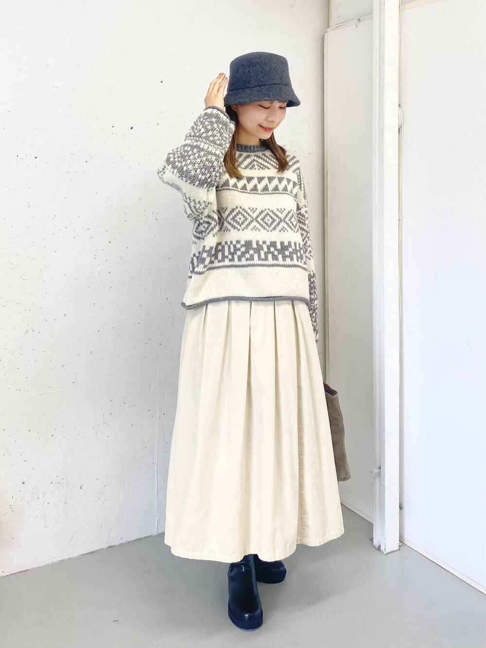 ベージュ系のトートバッグ、ブラック系のブーツ、ホワイト系のスカートを着用したレディースの秋コーディネートの4枚目の写真