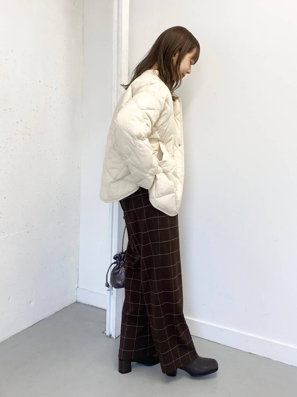 ホワイト系のダウンジャケット/コート、ホワイト系のニット/セーター、ブラウン系のブーツを着用したレディースの冬コーディネートの4枚目の写真
