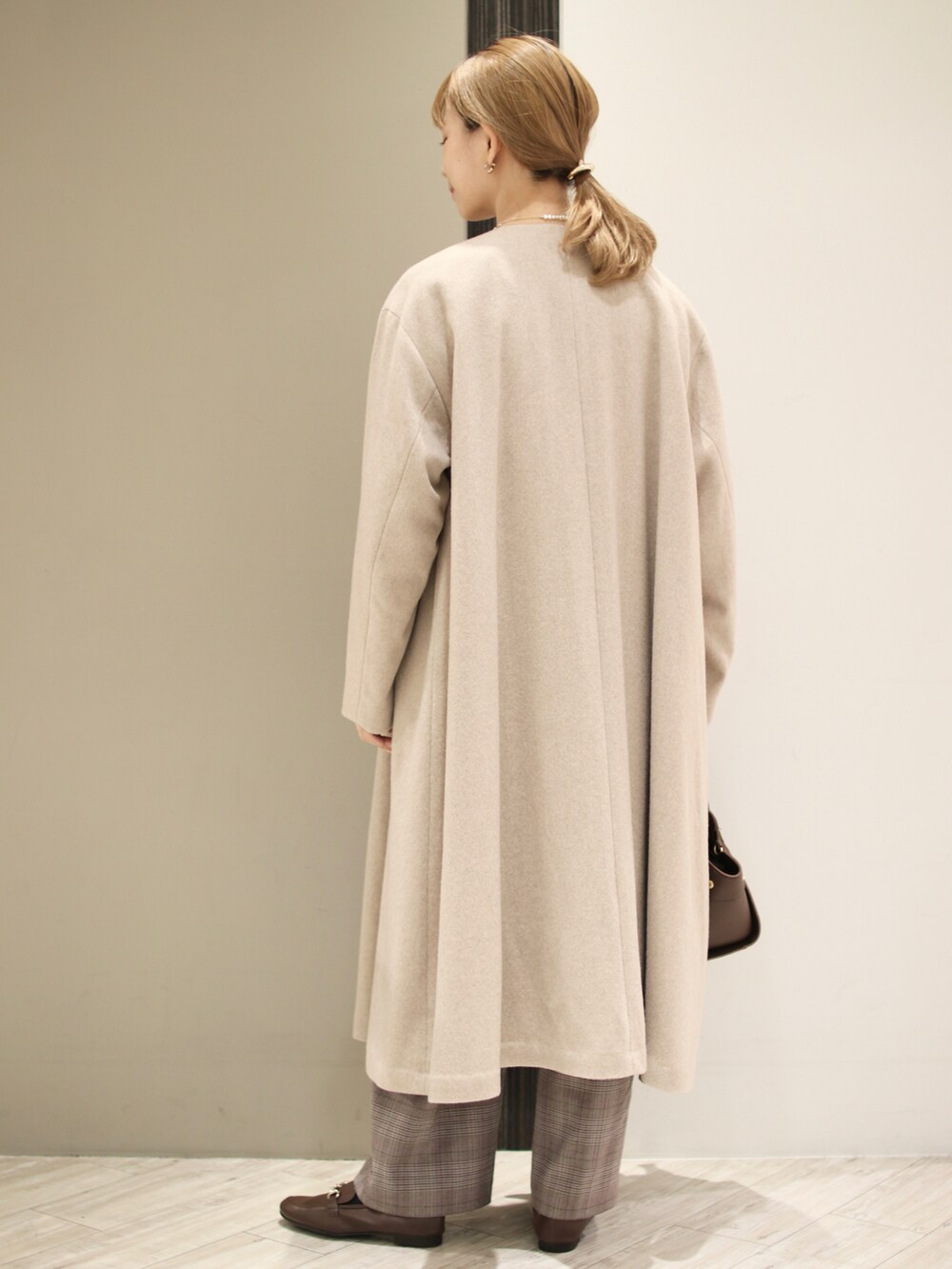 ブラウン系のハンドバッグ、パープル系のスウェット、ベージュ系のその他アウターを着用したレディースの冬コーディネートの5枚目の写真