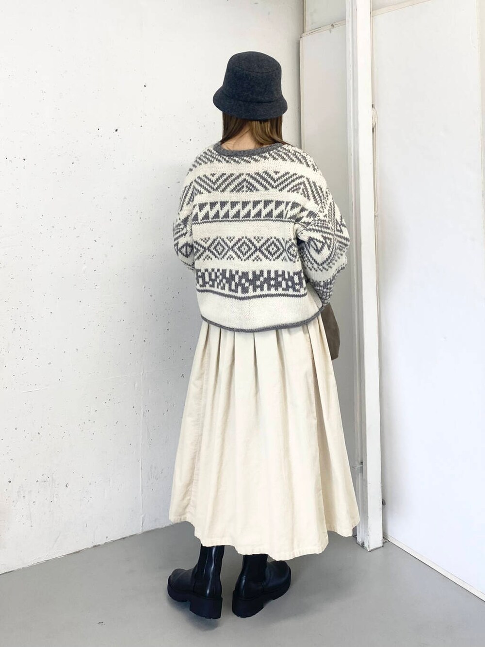 ベージュ系のトートバッグ、ブラック系のブーツ、ホワイト系のスカートを着用したレディースの秋コーディネートの6枚目の写真