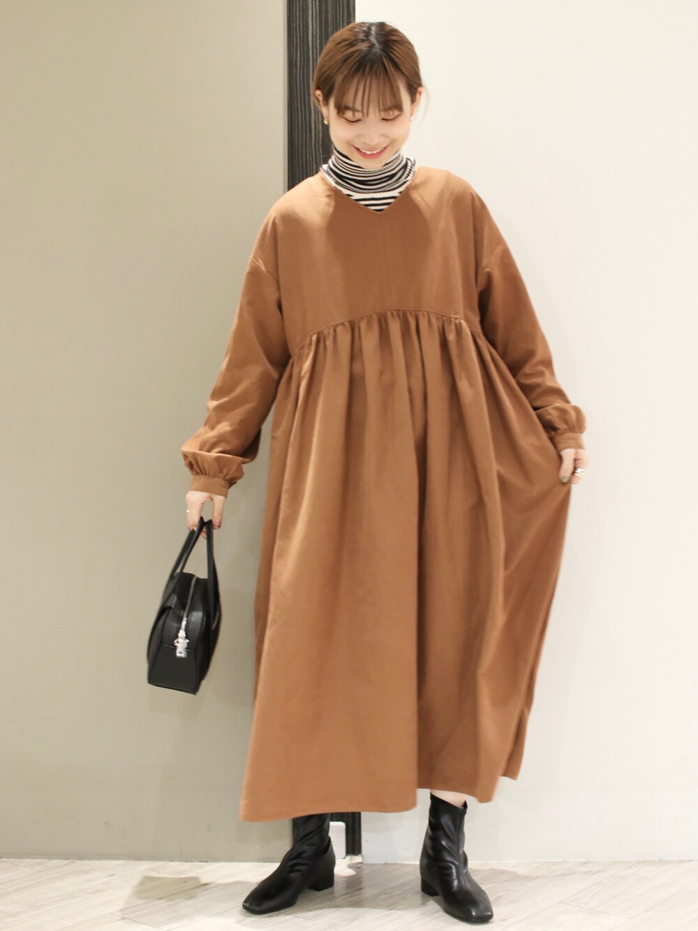 ブラック系のショルダーバッグ、イエロー系のワンピース、グレー系のニット/セーターを着用したレディースの冬コーディネートの2枚目の写真