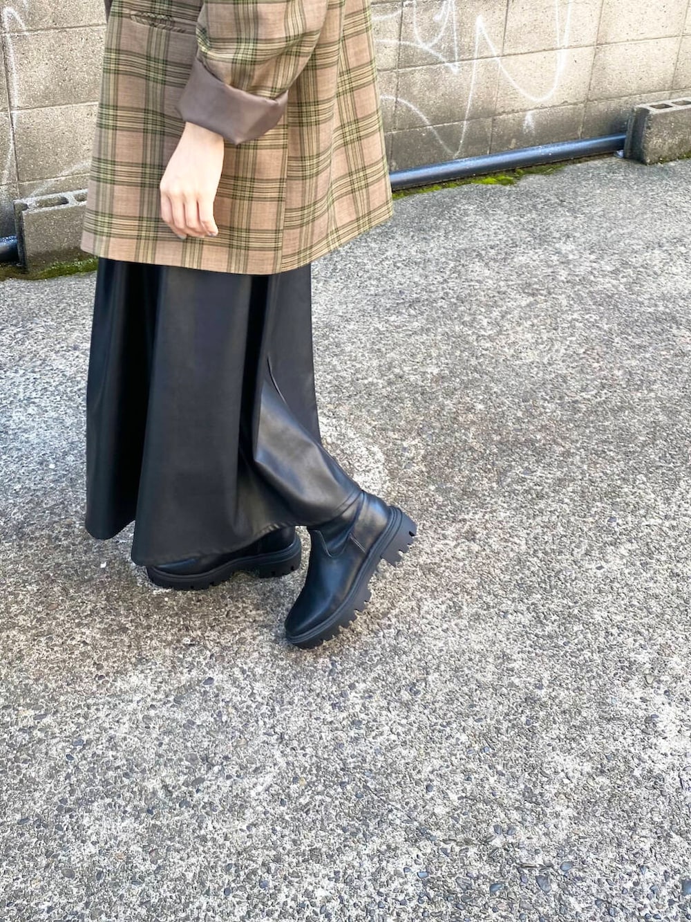 グリーン系のテーラードジャケット、ブラック系のブーツ、ブラック系のスカートを着用したレディースの秋コーディネートの6枚目の写真