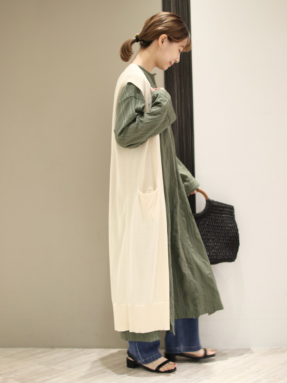 グリーン系のワンピース、ホワイト系のニット/セーター、ブラック系のトートバッグを着用したレディースの春コーディネートの4枚目の写真