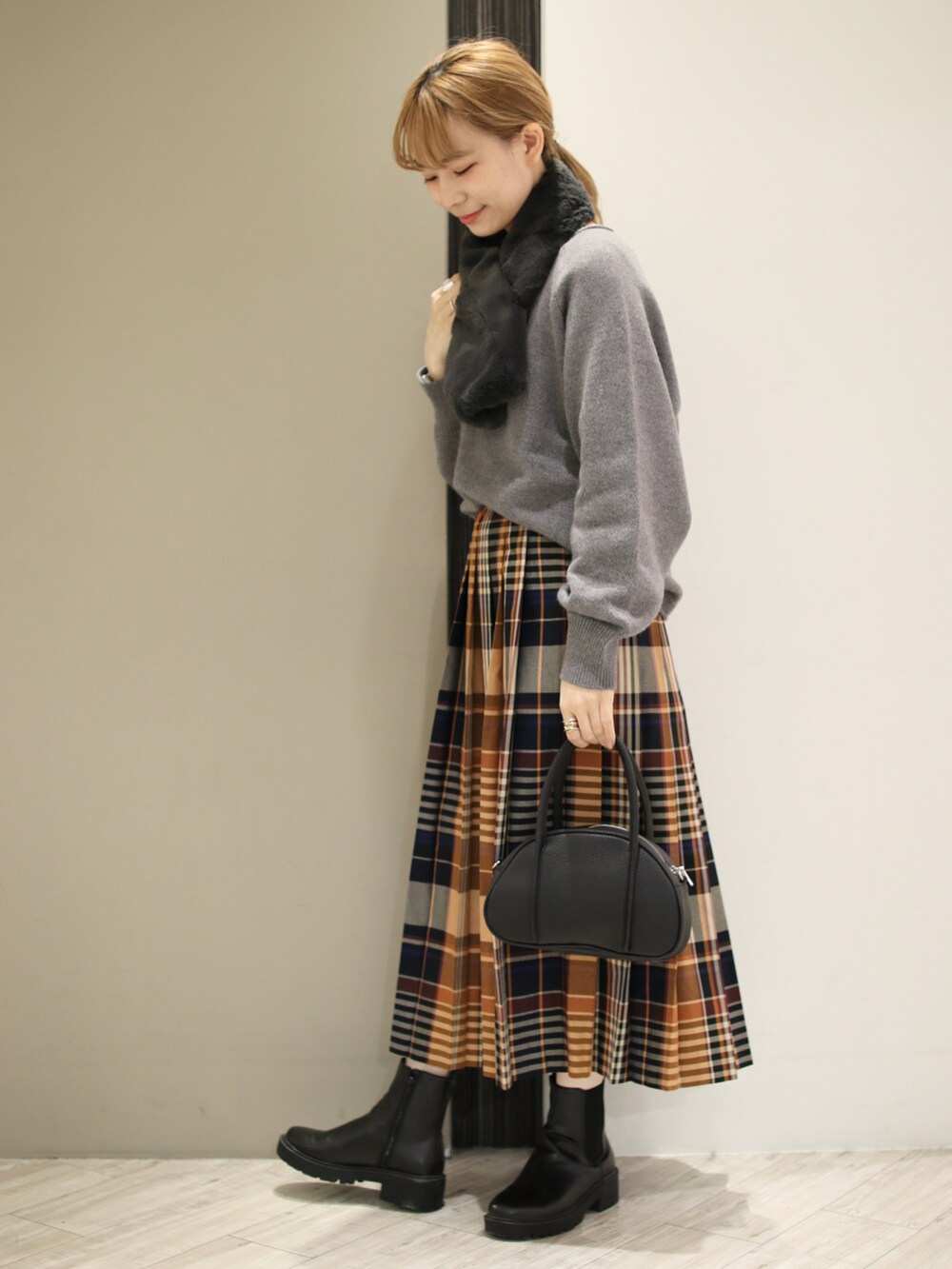 グレー系のニット/セーター、オレンジ系のスカート、ブラック系のショルダーバッグを着用したレディースの秋コーディネートの5枚目の写真