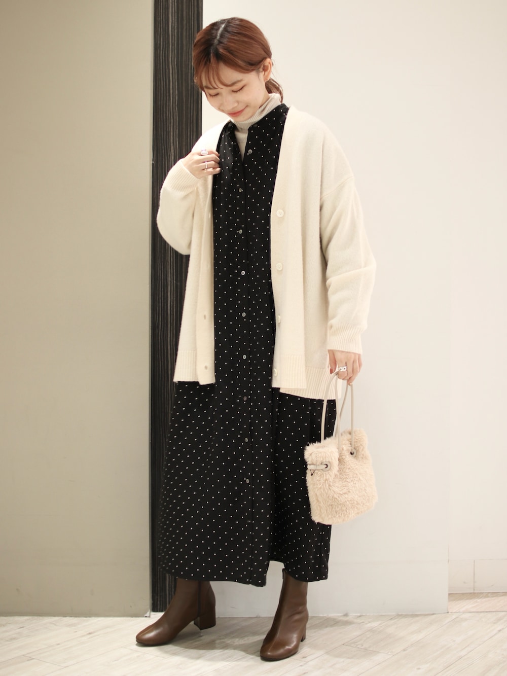 ベージュ系のハンドバッグ、ブラウン系のブーツ、ブラック系のワンピースを着用したレディースの冬コーディネートの2枚目の写真