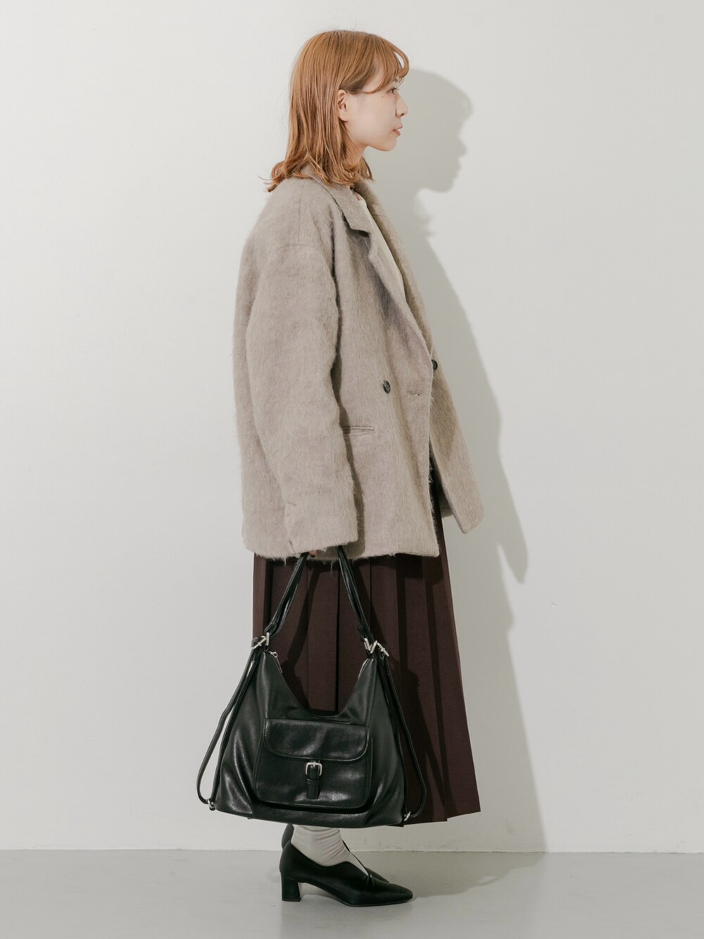 ブラウン系のスカート、ブラウン系のその他アウター、ホワイト系のTシャツ/カットソーを着用したレディースの秋コーディネートの4枚目の写真