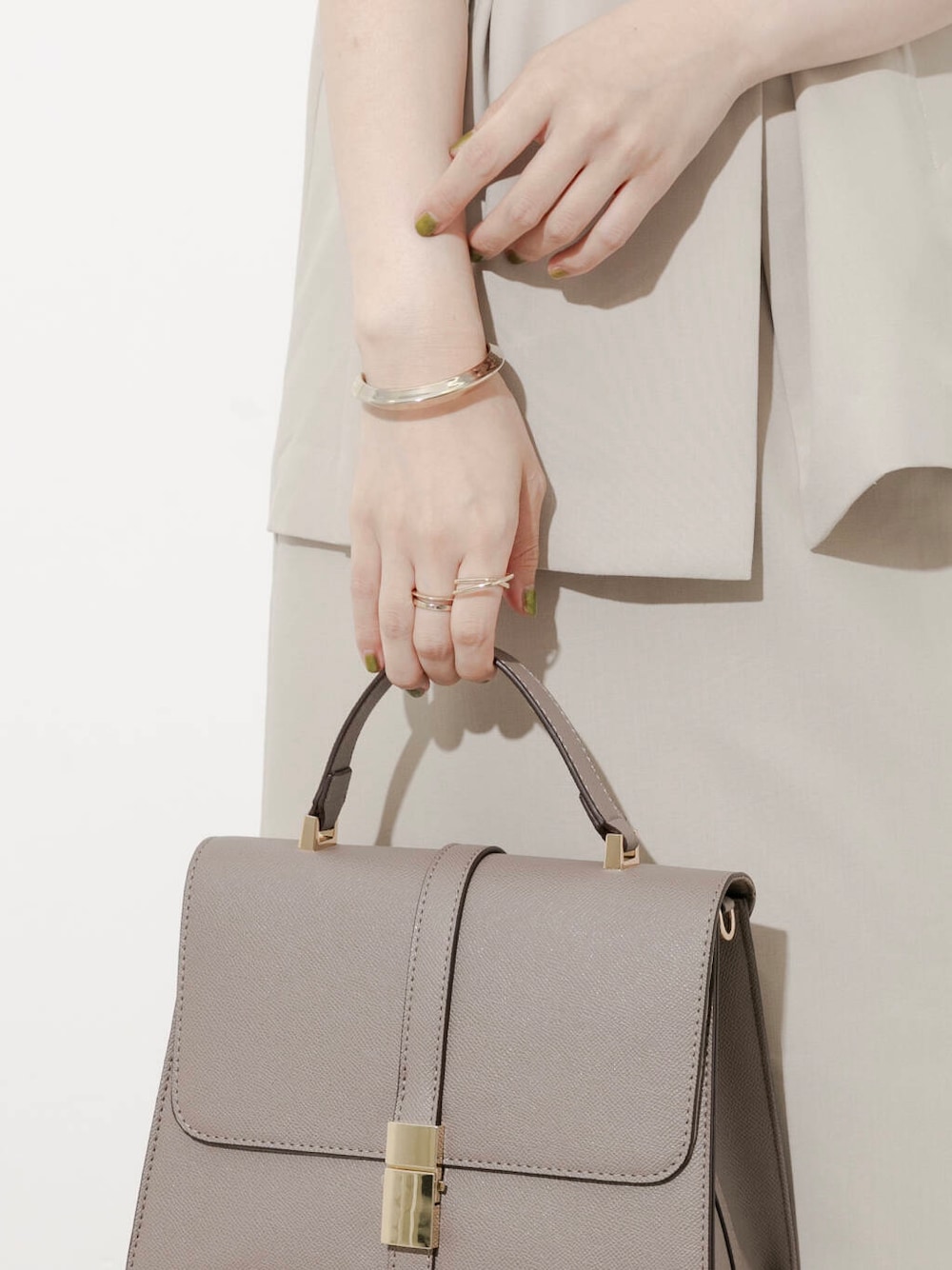 グレー系のハンドバッグ、ブラウン系のサンダル、ベージュ系のワンピースを着用したレディースの夏コーディネートの3枚目の写真