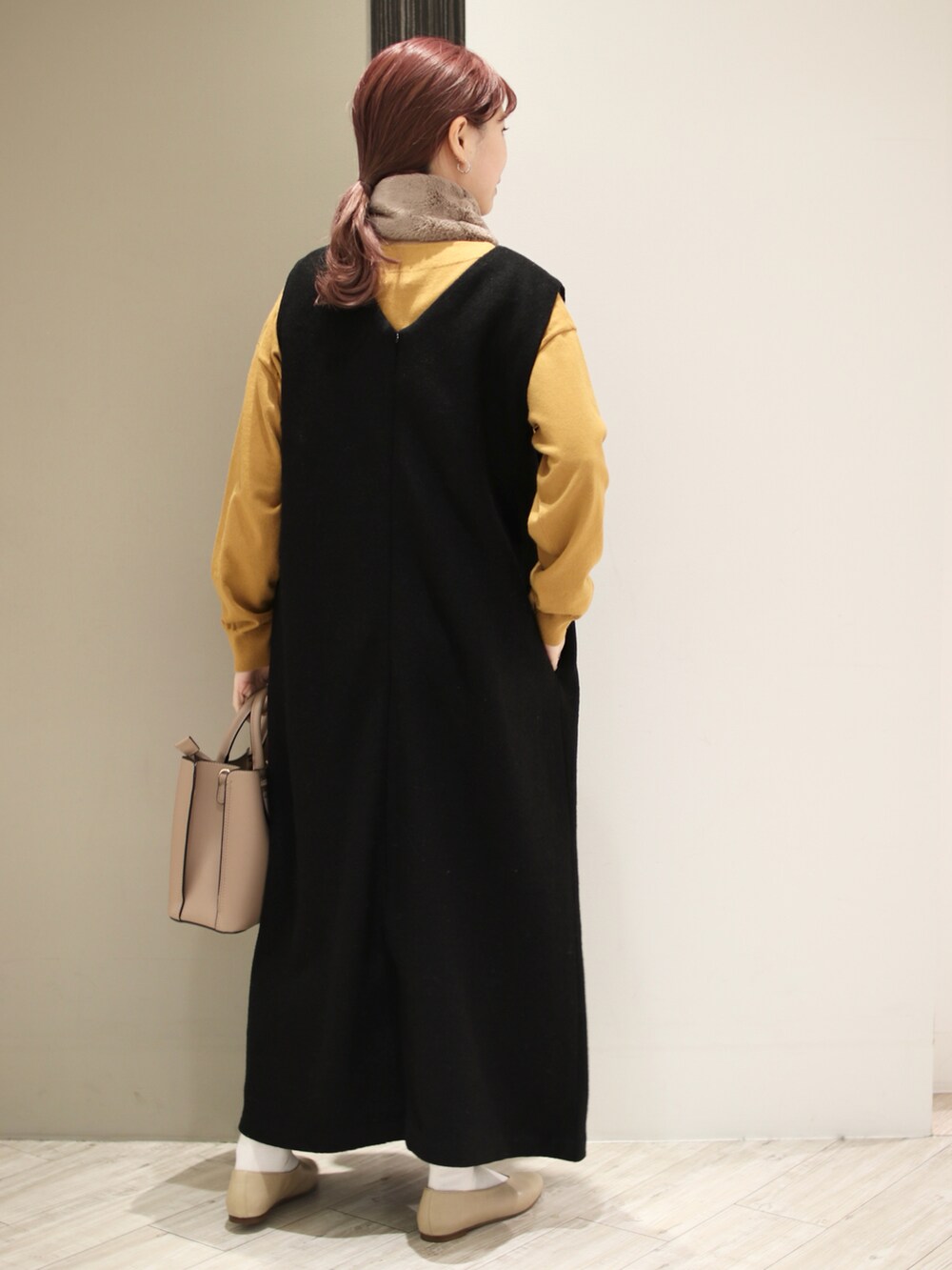 ブラウン系のトートバッグ、ブラック系のワンピース、イエロー系のニット/セーターを着用したレディースの冬コーディネートの4枚目の写真