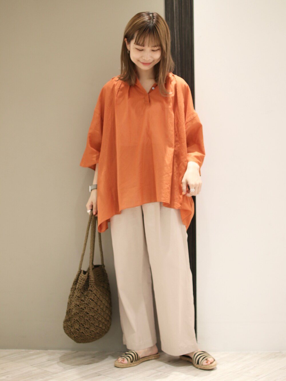 オレンジ系のシャツ/ブラウス、ベージュ系のその他パンツ、グリーン系のトートバッグを着用したレディースの夏コーディネートの4枚目の写真