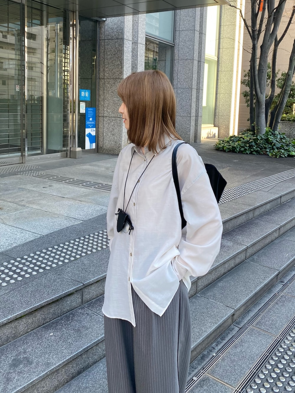ブラック系のトートバッグ、ブラック系のローファー、グレー系のその他パンツを着用したレディースの春コーディネートの4枚目の写真