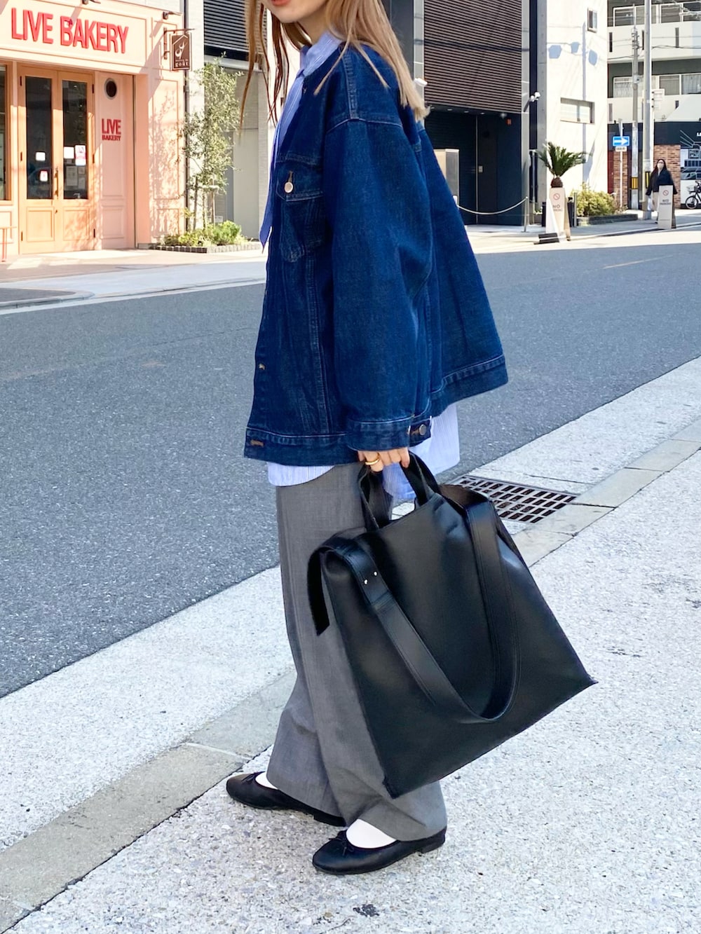 グレー系のパンツ、ブラック系のトートバッグ、ブルー系のシャツ/ブラウスを着用したレディースの春コーディネートの5枚目の写真