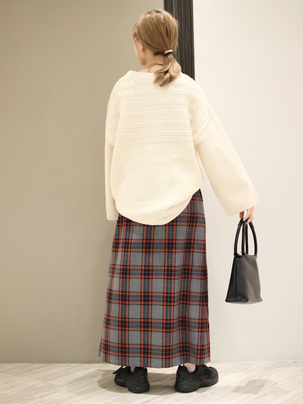ホワイト系のニット/セーター、グレー系のスカート、ブラック系のハンドバッグを着用したレディースの秋コーディネートの2枚目の写真