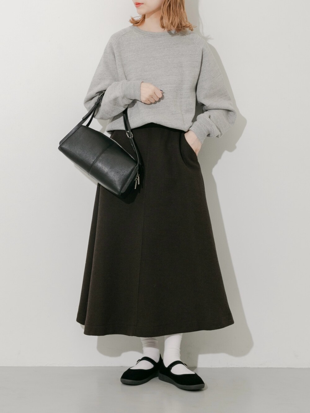 グレー系のスカート、ブラック系のその他シューズ、グレー系のスウェットを着用したレディースの秋コーディネートの3枚目の写真