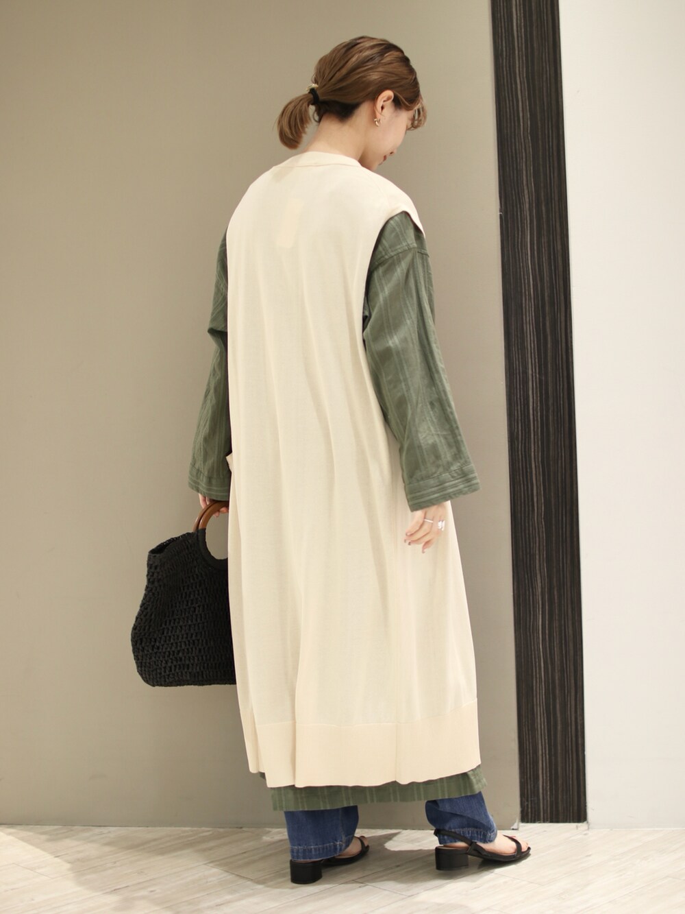 グリーン系のワンピース、ホワイト系のニット/セーター、ブラック系のトートバッグを着用したレディースの春コーディネートの3枚目の写真