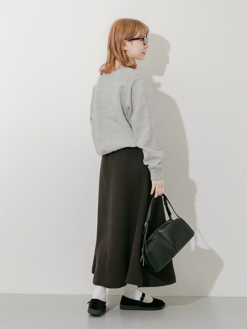 グレー系のスカート、ブラック系のその他シューズ、グレー系のスウェットを着用したレディースの秋コーディネートの4枚目の写真