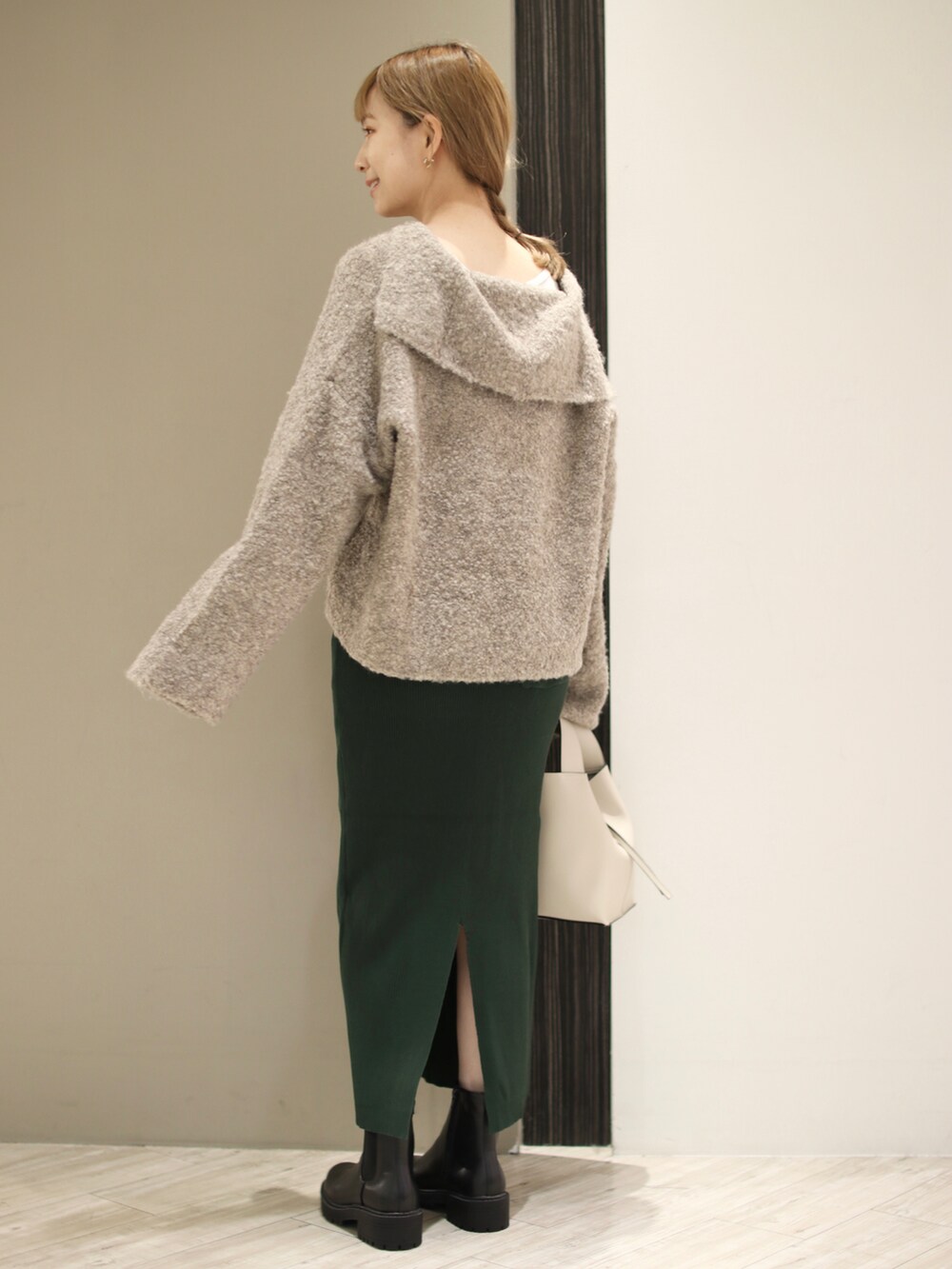 ホワイト系のトートバッグ、ブラック系のブーツ、グリーン系のスカートを着用したレディースの秋コーディネートの4枚目の写真