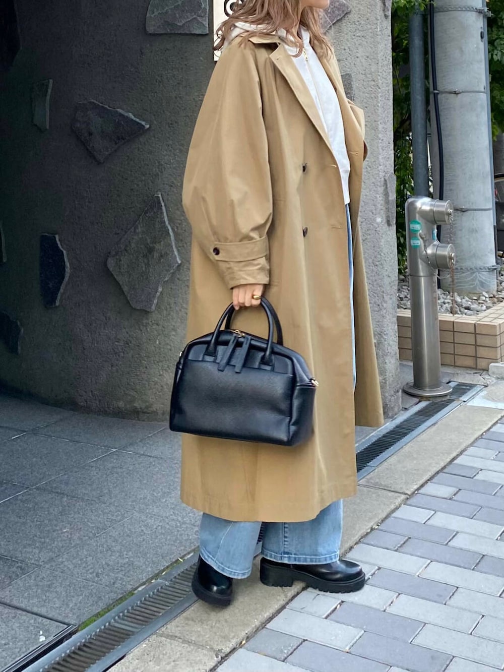 ブラック系のボストンバッグ、ブラック系のブーツ、ベージュ系のパーカーを着用したレディースの冬コーディネートの3枚目の写真