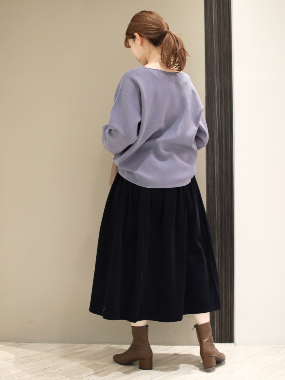 ベージュ系のトートバッグ、ブルー系のスカート、ブルー系のニット/セーターを着用したレディースの秋コーディネートの3枚目の写真