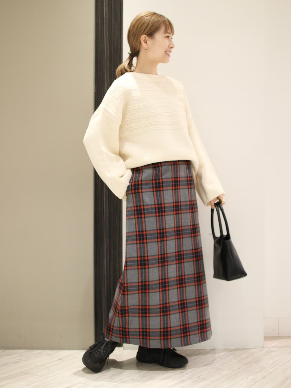 ホワイト系のニット/セーター、グレー系のスカート、ブラック系のハンドバッグを着用したレディースの秋コーディネートの3枚目の写真
