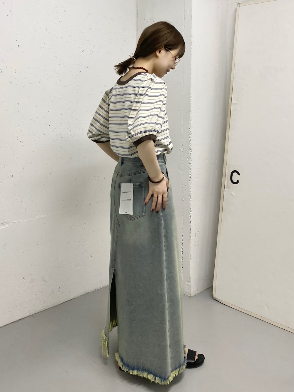 ブルー系のスカート、ホワイト系のTシャツ/カットソー、ゴールド系のリングを着用したレディースの春コーディネートの2枚目の写真