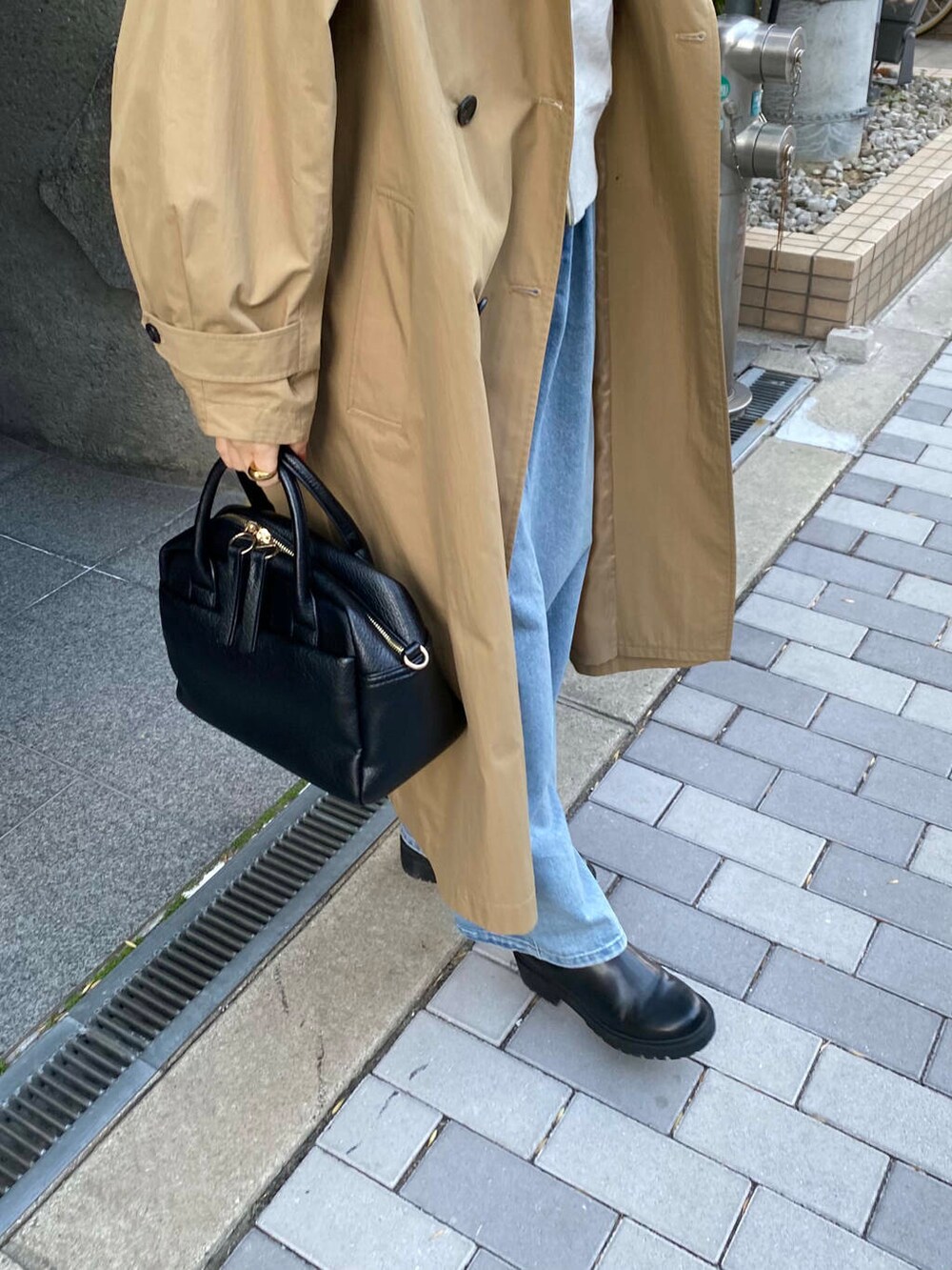 ブラック系のボストンバッグ、ブラック系のブーツ、ベージュ系のパーカーを着用したレディースの冬コーディネートの6枚目の写真