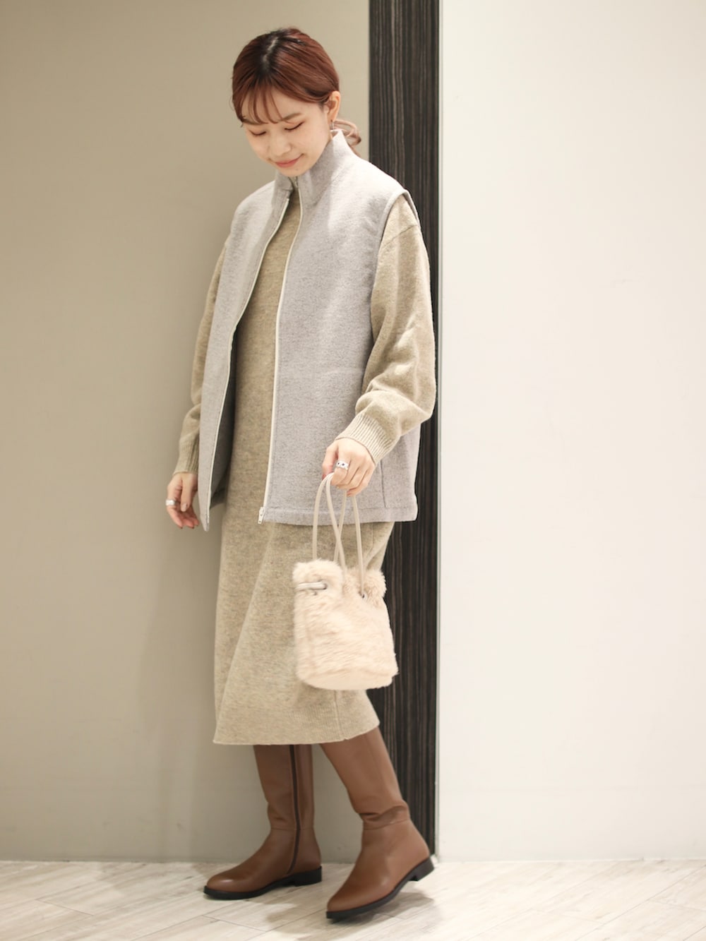 ベージュ系のハンドバッグ、ブラウン系のブーツ、ホワイト系のワンピースを着用したレディースの冬コーディネートの3枚目の写真