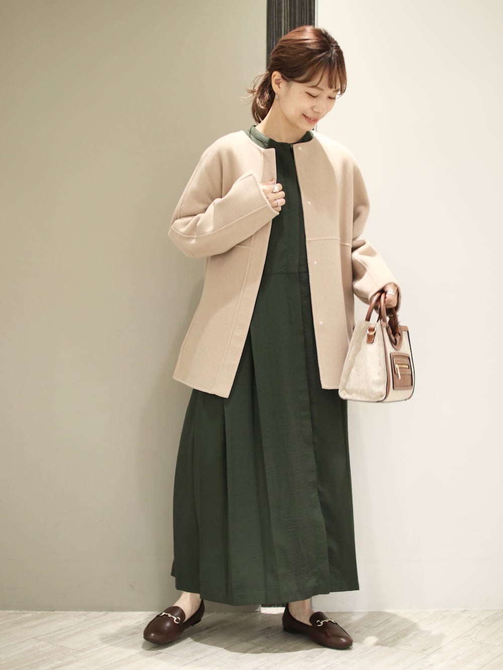 ブラウン系のトートバッグ、ブラウン系のローファー、グリーン系のワンピースを着用したレディースの秋コーディネートの2枚目の写真