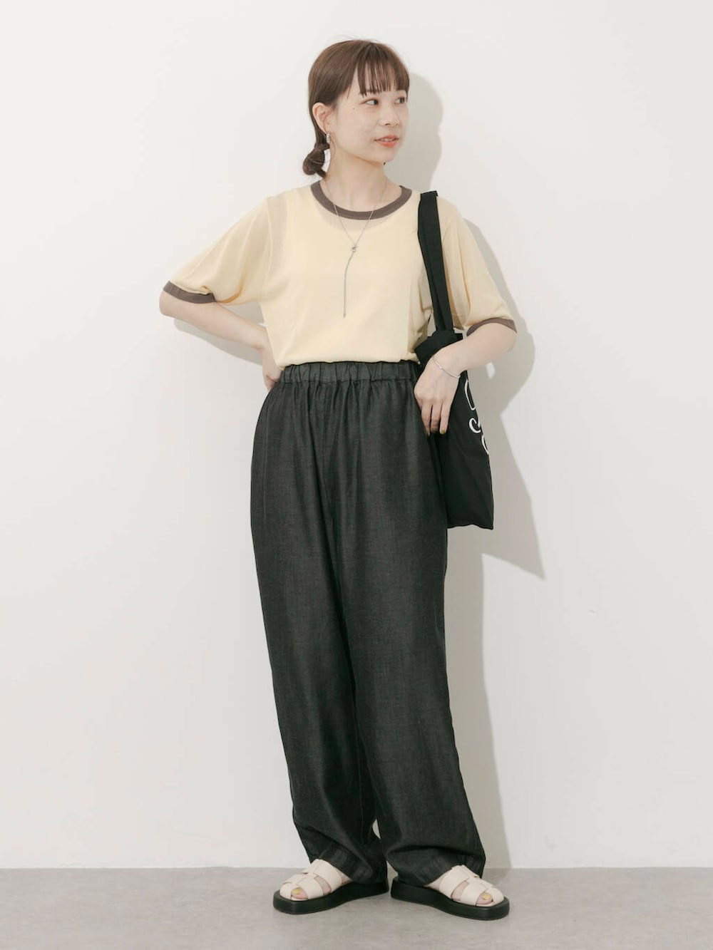 ブラック系のトートバッグ、ベージュ系のニット/セーター、ホワイト系のサンダルを着用したレディースの夏コーディネートの3枚目の写真