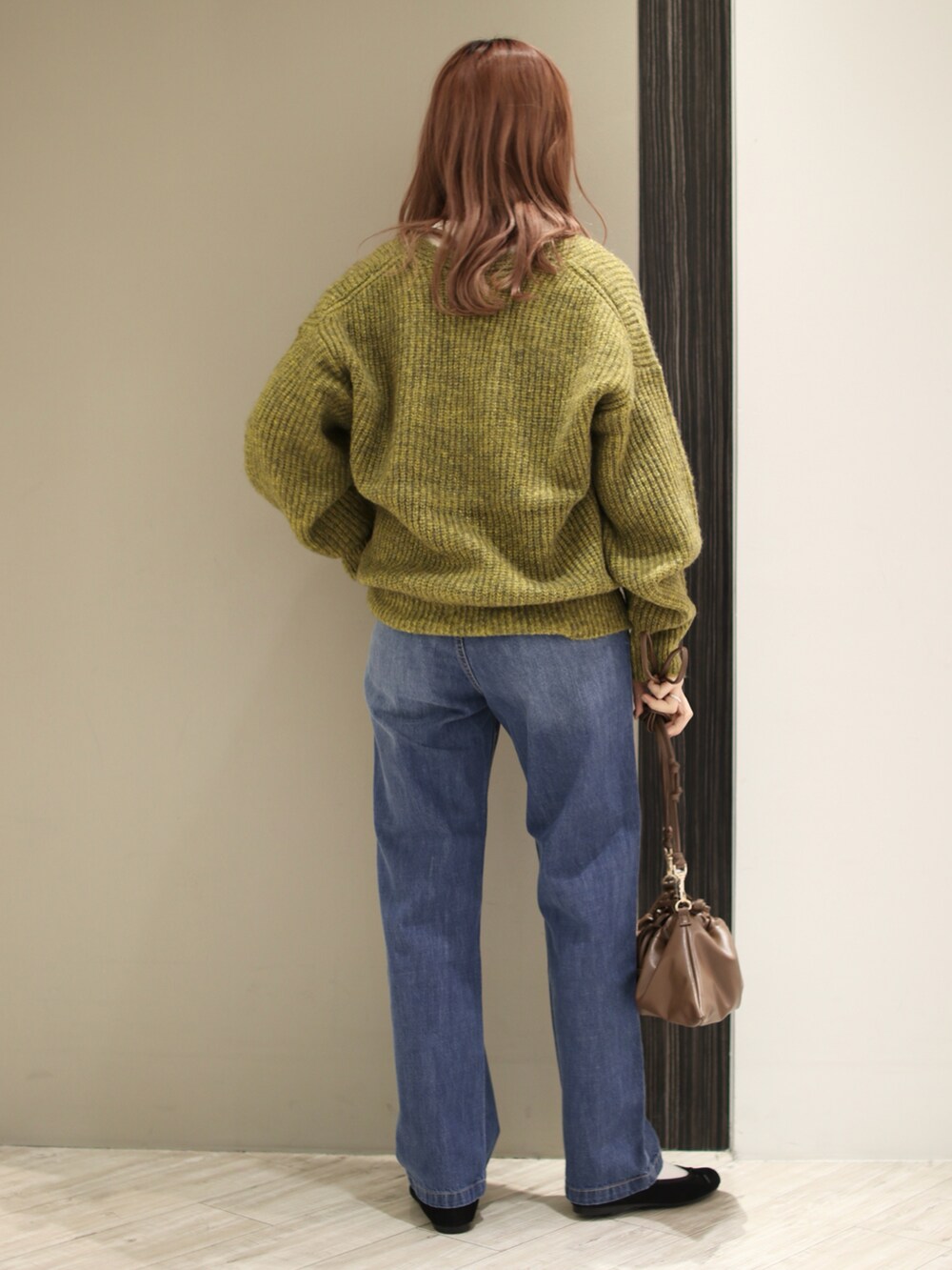 ブルー系のデニムパンツ、ブラウン系のハンドバッグ、ブラック系のバレエシューズを着用したレディースの冬コーディネートの3枚目の写真