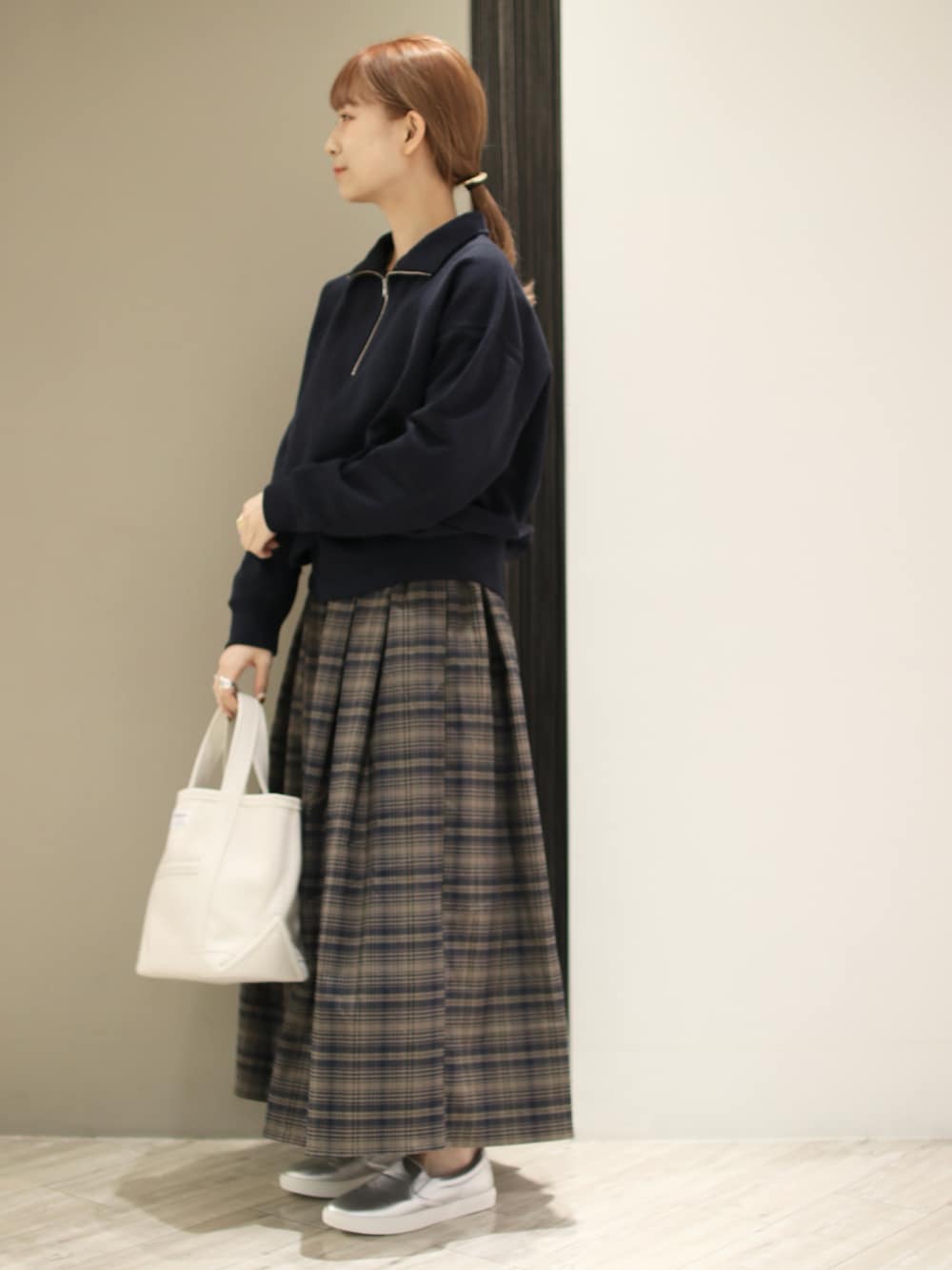 ブラウン系のスカート、ブルー系のスウェット、ベージュ系のトートバッグを着用したレディースの秋コーディネートの3枚目の写真