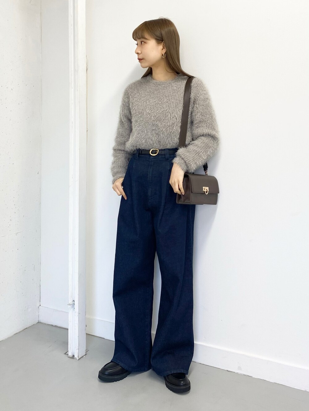 ブラック系のローファー、ブルー系のデニムパンツ、グレー系のニット/セーターを着用したレディースの冬コーディネートの4枚目の写真