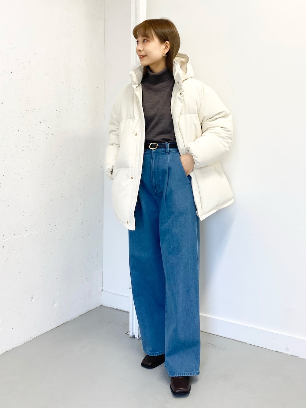 ブラウン系のブーツ、ブラウン系のニット/セーター、ホワイト系のダウンジャケット/コートを着用したレディースの冬コーディネートの3枚目の写真