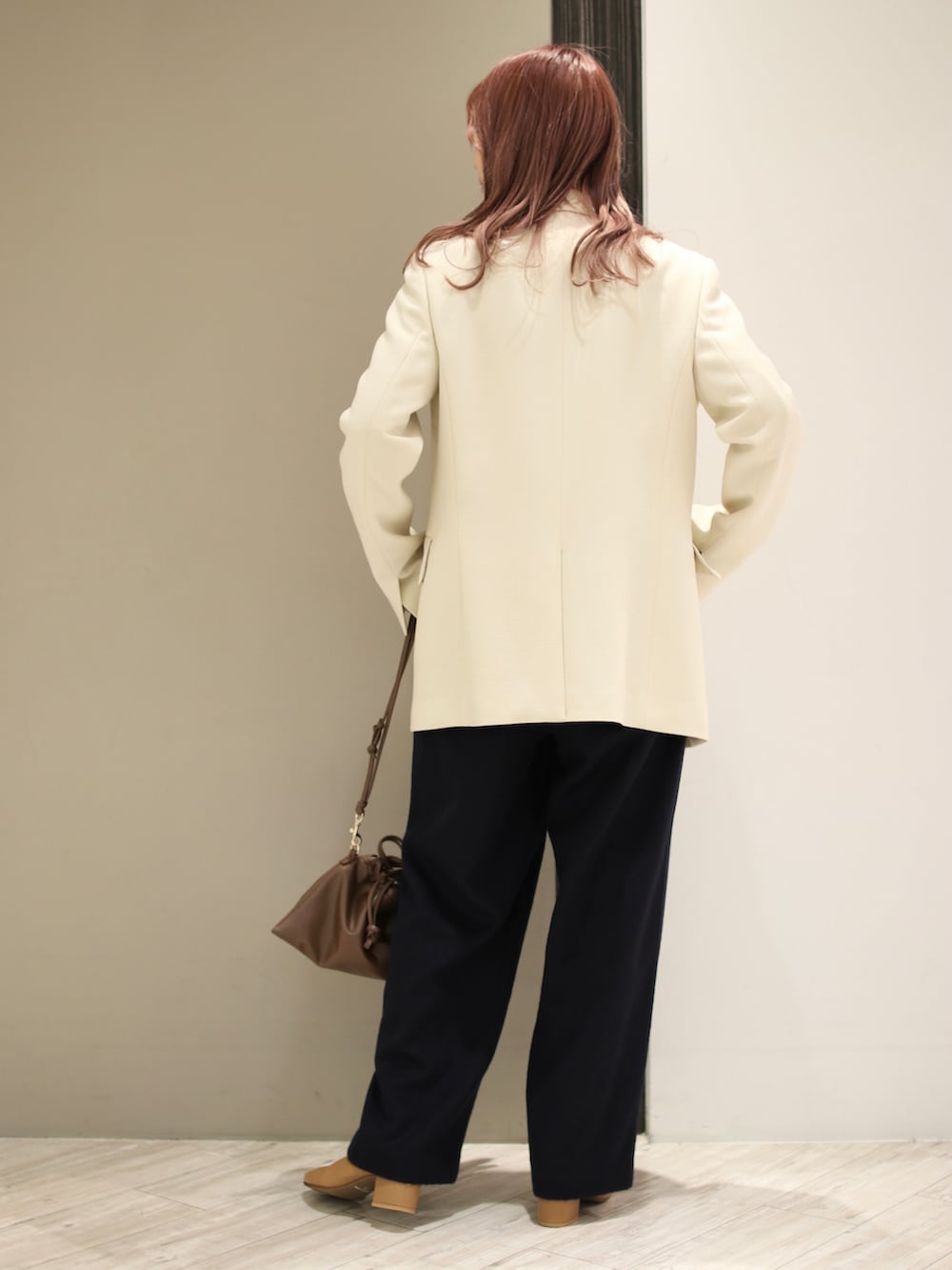 イエロー系のニット/セーター、ブラウン系のハンドバッグ、イエロー系のブーツを着用したレディースの冬コーディネートの3枚目の写真