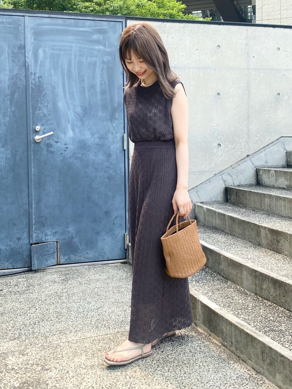 イエロー系のハンドバッグ、ベージュ系のサンダル、グレー系のスカートを着用したレディースの夏コーディネートの4枚目の写真