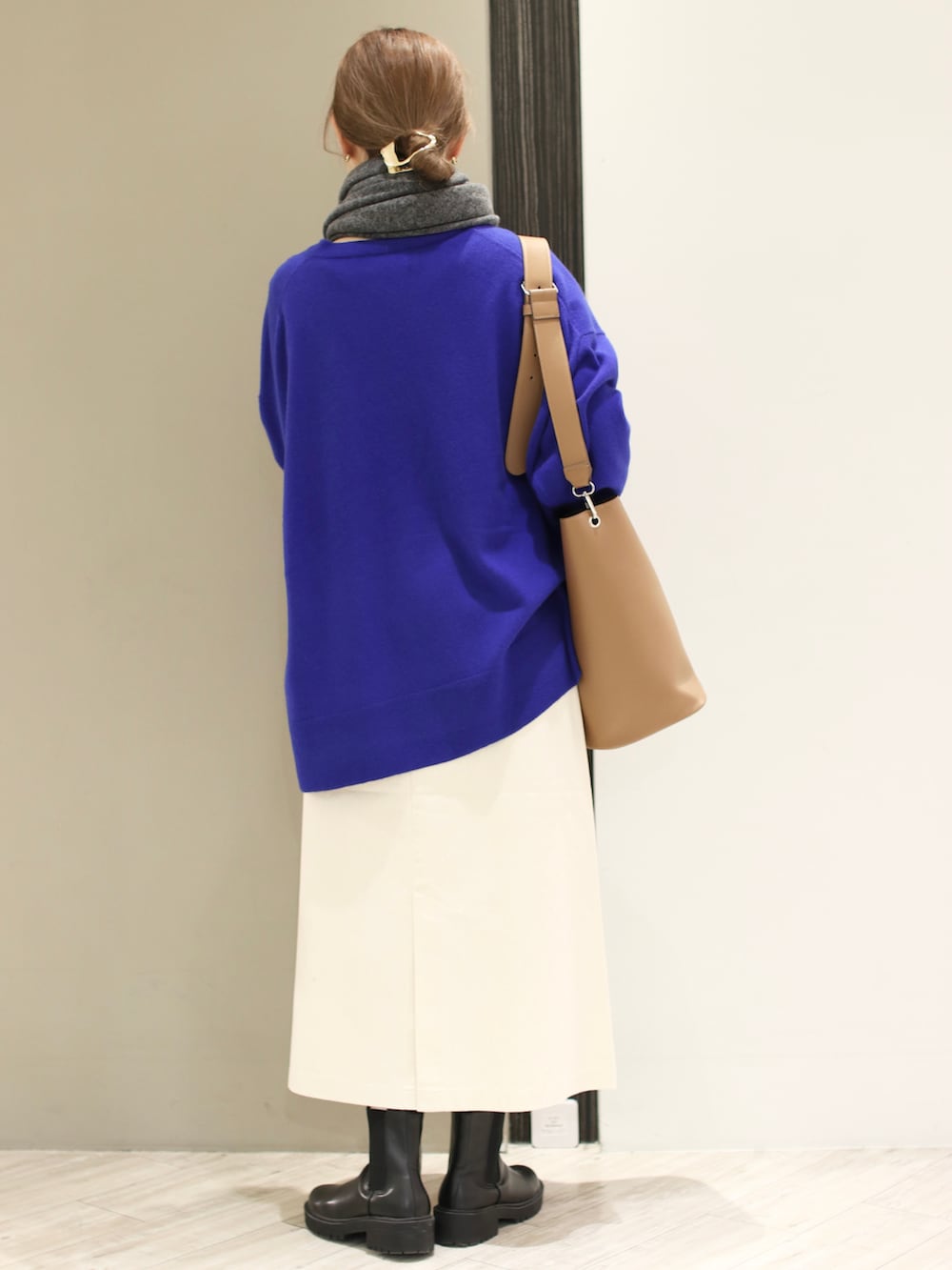 ブラウン系のショルダーバッグ、ホワイト系のスカート、ブラック系のブーツを着用したレディースの冬コーディネートの4枚目の写真