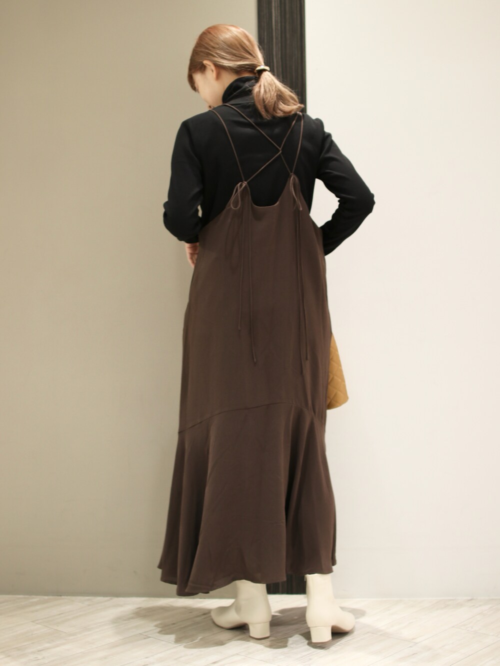 ベージュ系のショルダーバッグ、ベージュ系のブーツ、ブラック系のTシャツ/カットソーを着用したレディースの秋コーディネートの3枚目の写真