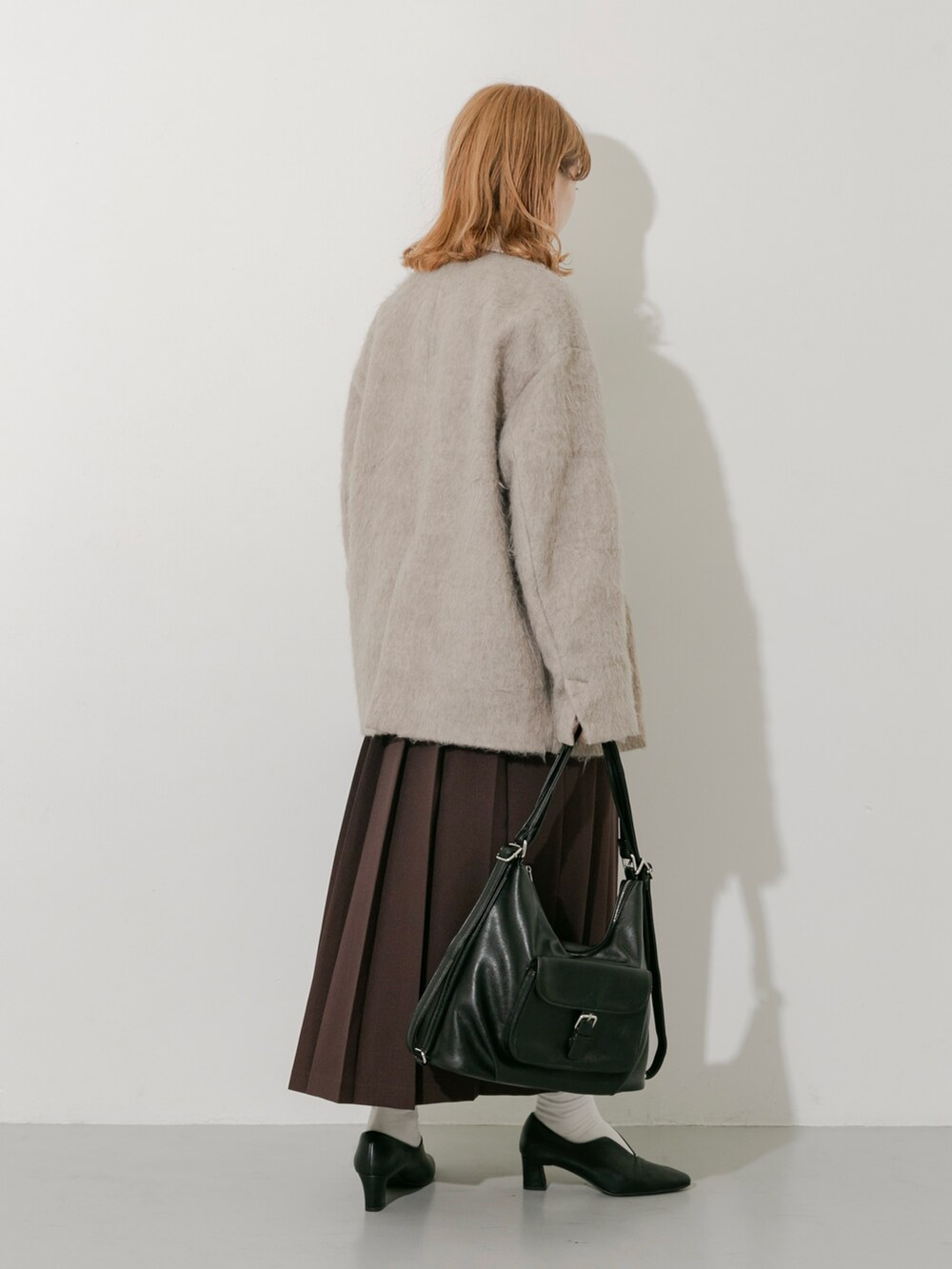 ブラウン系のスカート、ブラウン系のその他アウター、ホワイト系のTシャツ/カットソーを着用したレディースの秋コーディネートの6枚目の写真