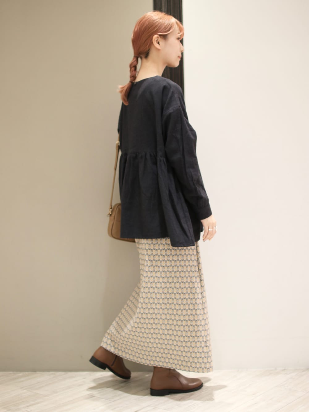 イエロー系のスカート、ブラウン系のブーツ、グレー系のシャツ/ブラウスを着用したレディースの冬コーディネートの2枚目の写真