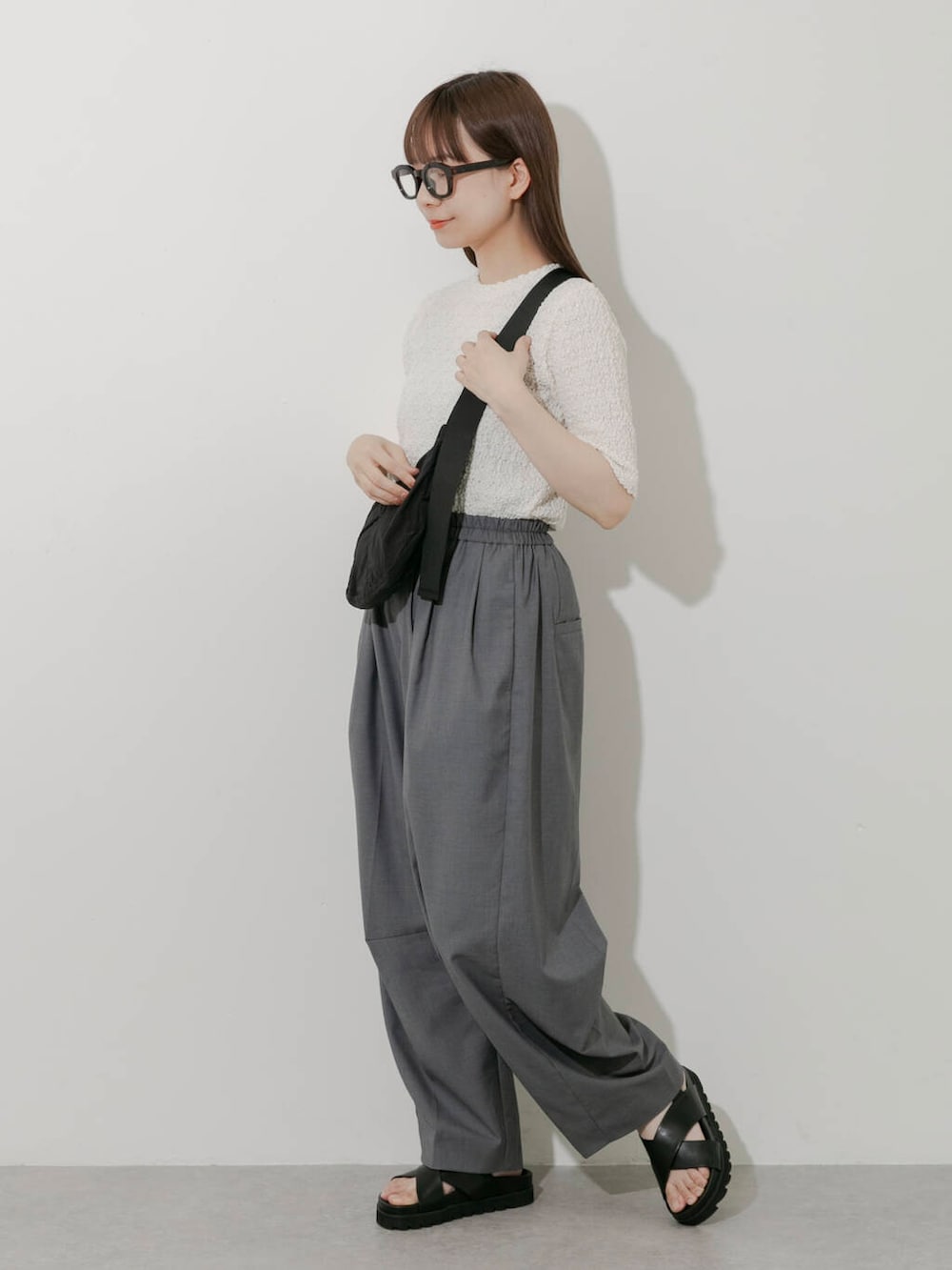 グレー系のその他パンツ、ホワイト系のTシャツ/カットソー、ブラック系のサンダルを着用したレディースの春コーディネートの2枚目の写真