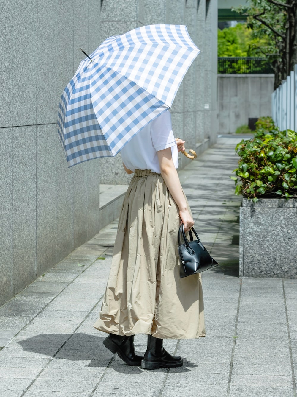 ホワイト系のポロシャツ、ブラック系のショルダーバッグ、ベージュ系のスカートを着用したレディースの春コーディネートの3枚目の写真