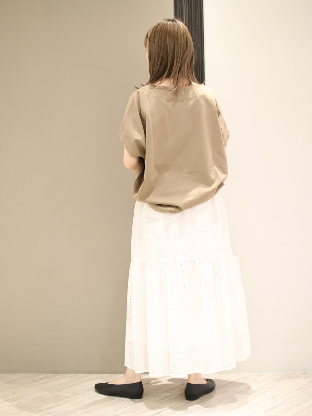 ブラウン系のトートバッグ、ベージュ系のTシャツ/カットソー、ホワイト系のスカートを着用したレディースの夏コーディネートの3枚目の写真