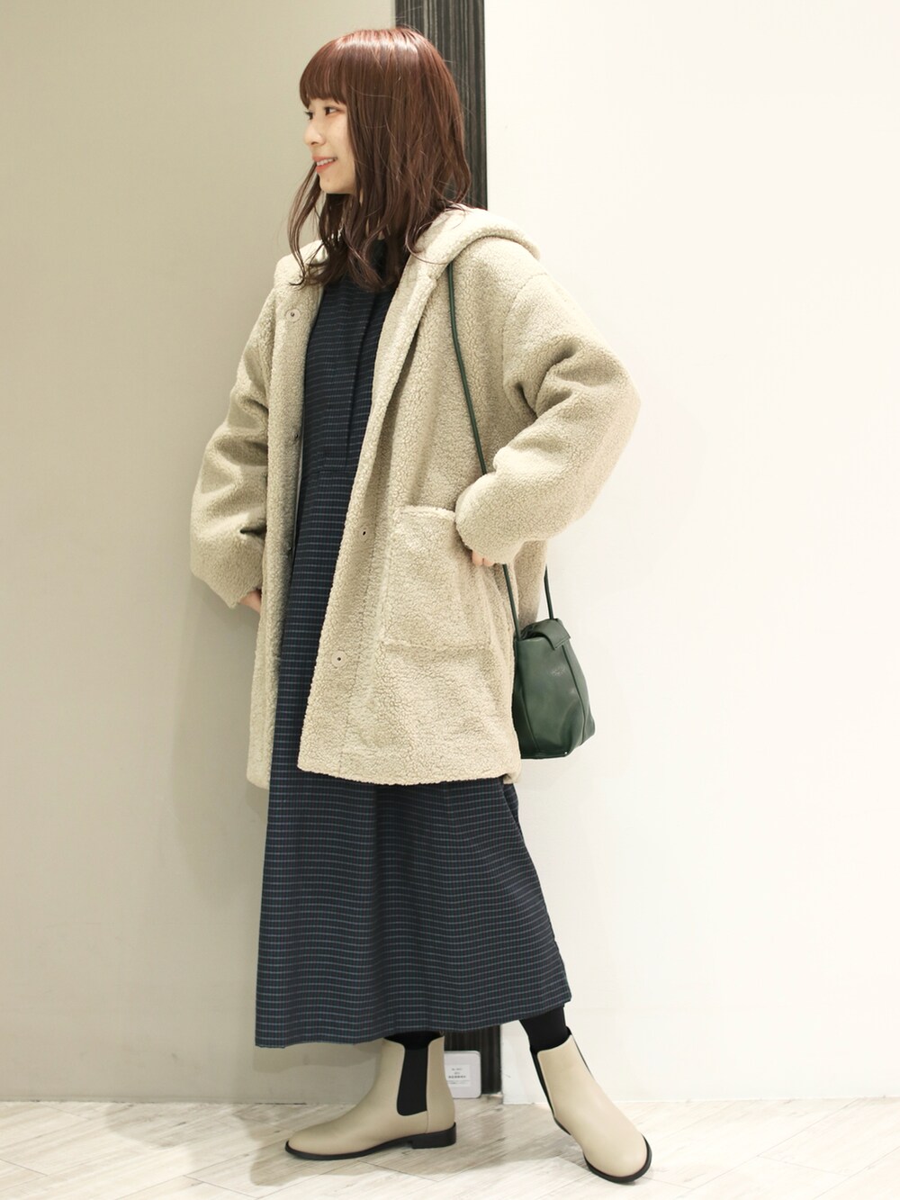 ブルー系のワンピース、ベージュ系のその他アウター、ベージュ系のブーツを着用したレディースの冬コーディネートの2枚目の写真