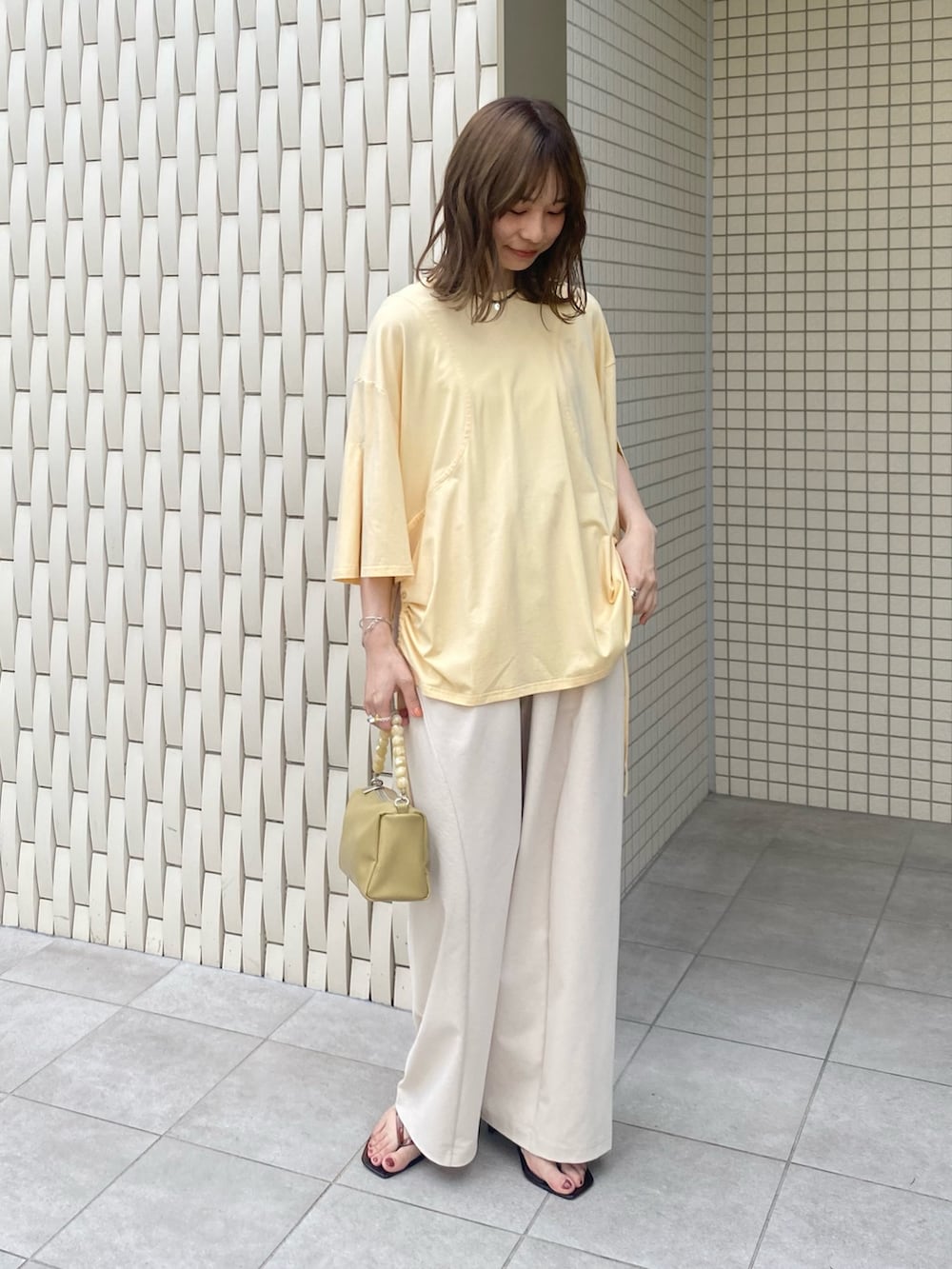 ブラウン系のサンダル、ベージュ系のショルダーバッグ、イエロー系のTシャツ/カットソーを着用したレディースの夏コーディネートの4枚目の写真