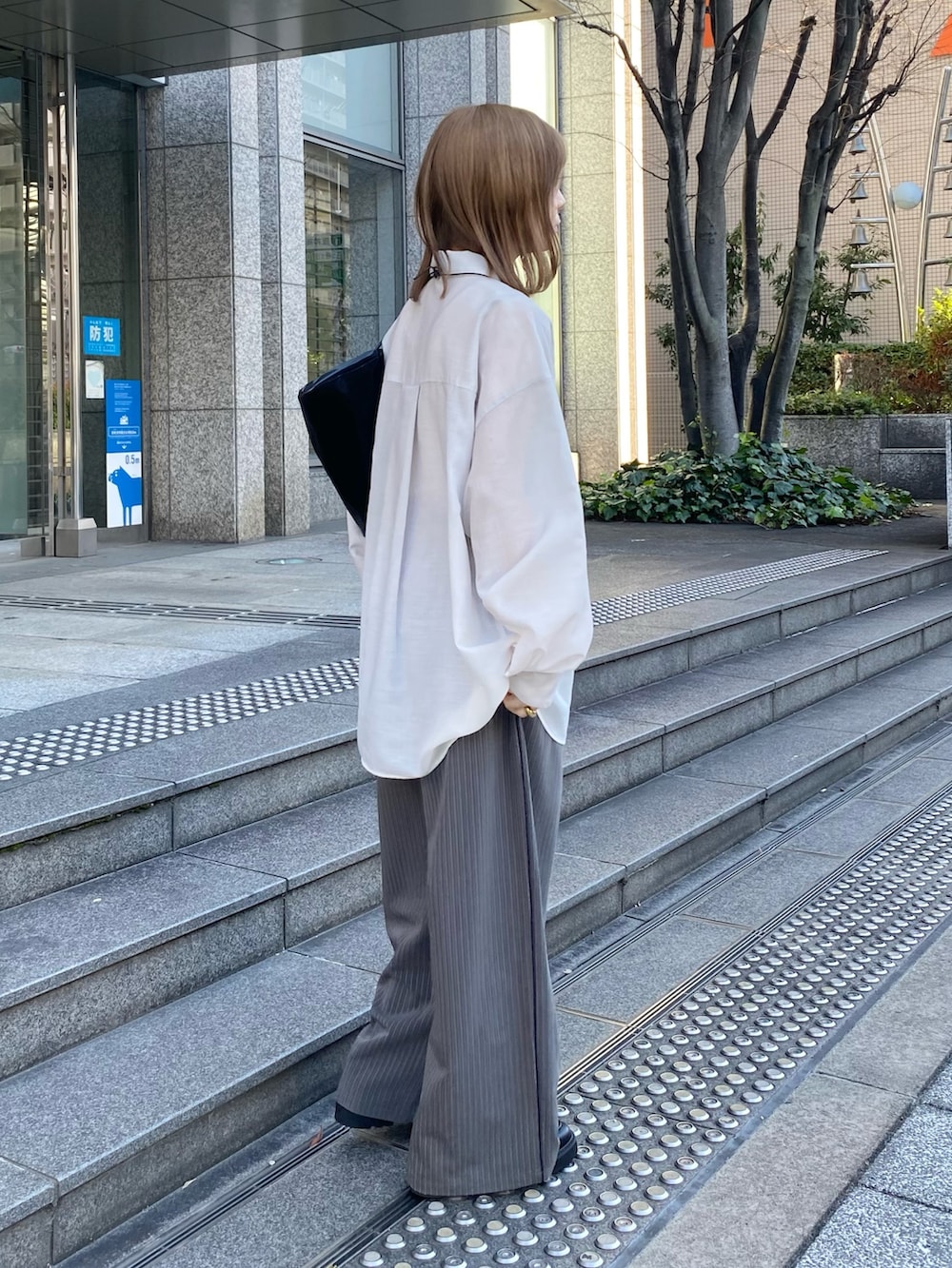 ブラック系のトートバッグ、ブラック系のローファー、グレー系のその他パンツを着用したレディースの春コーディネートの3枚目の写真