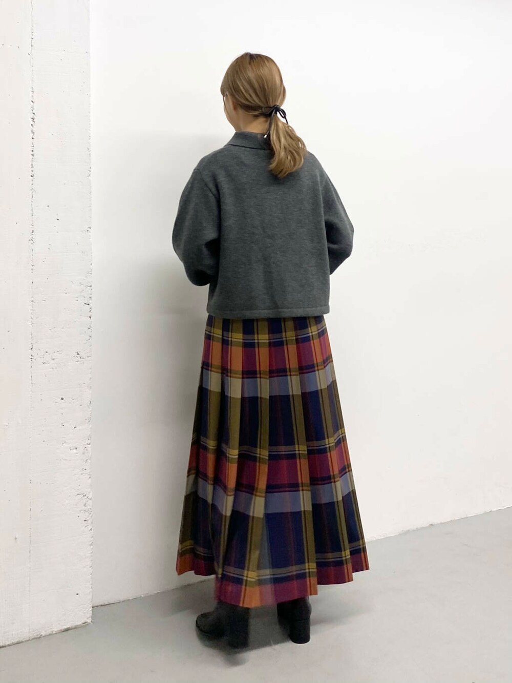 ブラック系のボストンバッグ、ブラック系のブーツ、ブルー系のスカートを着用したレディースの秋コーディネートの3枚目の写真