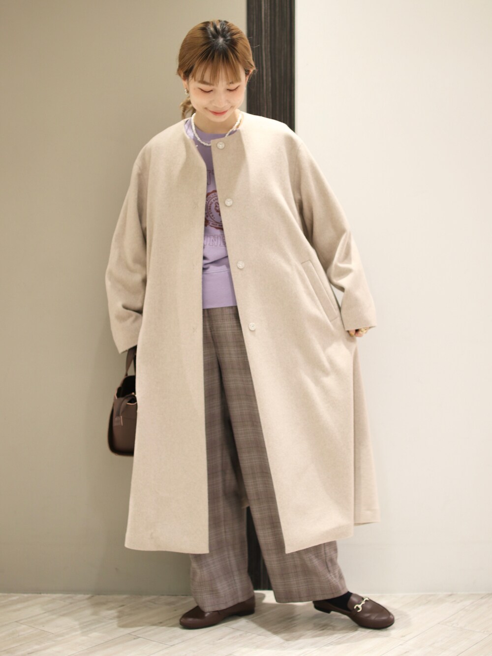 ブラウン系のハンドバッグ、パープル系のスウェット、ベージュ系のその他アウターを着用したレディースの冬コーディネートの2枚目の写真