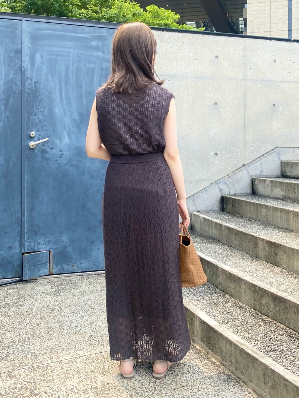 イエロー系のハンドバッグ、ベージュ系のサンダル、グレー系のスカートを着用したレディースの夏コーディネートの3枚目の写真