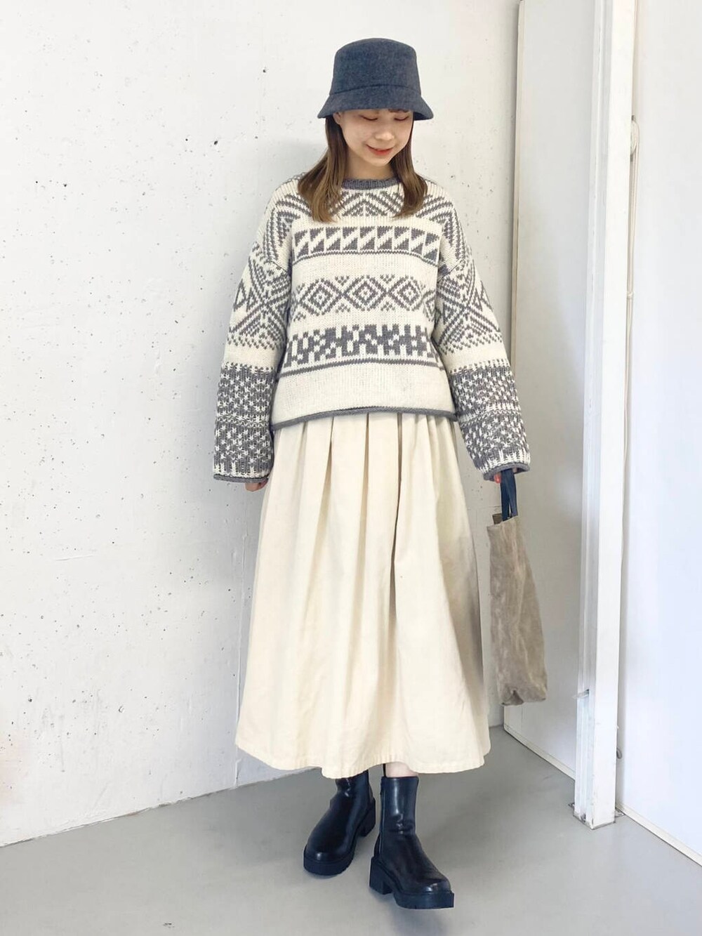 ベージュ系のトートバッグ、ブラック系のブーツ、ホワイト系のスカートを着用したレディースの秋コーディネートの7枚目の写真